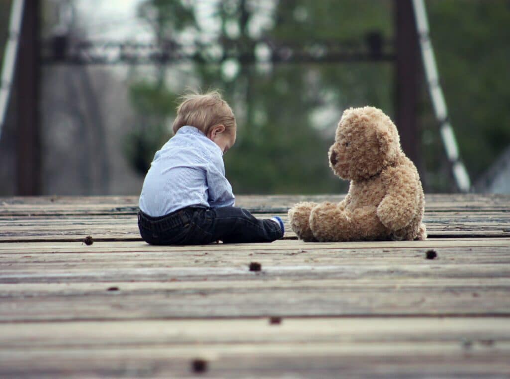 Baby playing outside with teddy bear