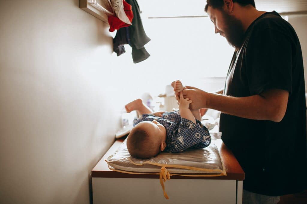 Dad changing baby's diaper on changing table
