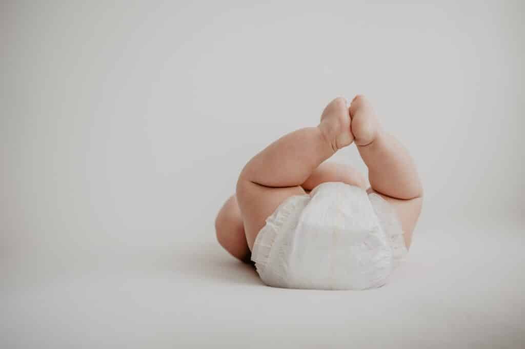 Baby in diaper laying on bed
