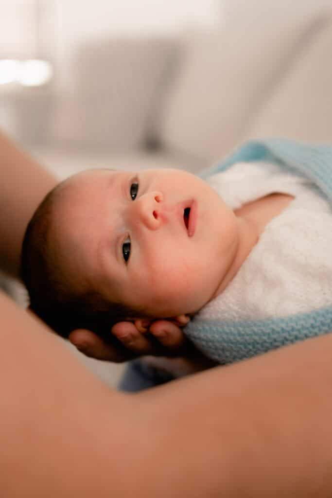 Adult holding a swaddled newborn baby