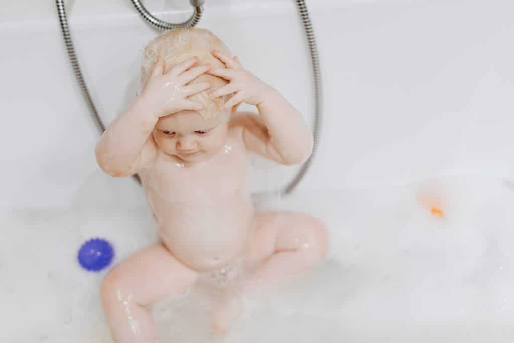 Baby in a bath tub with soapy hair and bubles