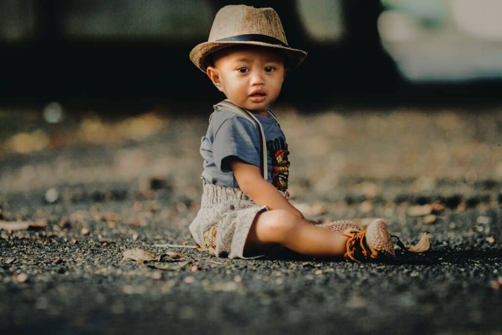 Baby boy in hat sitting on the ground