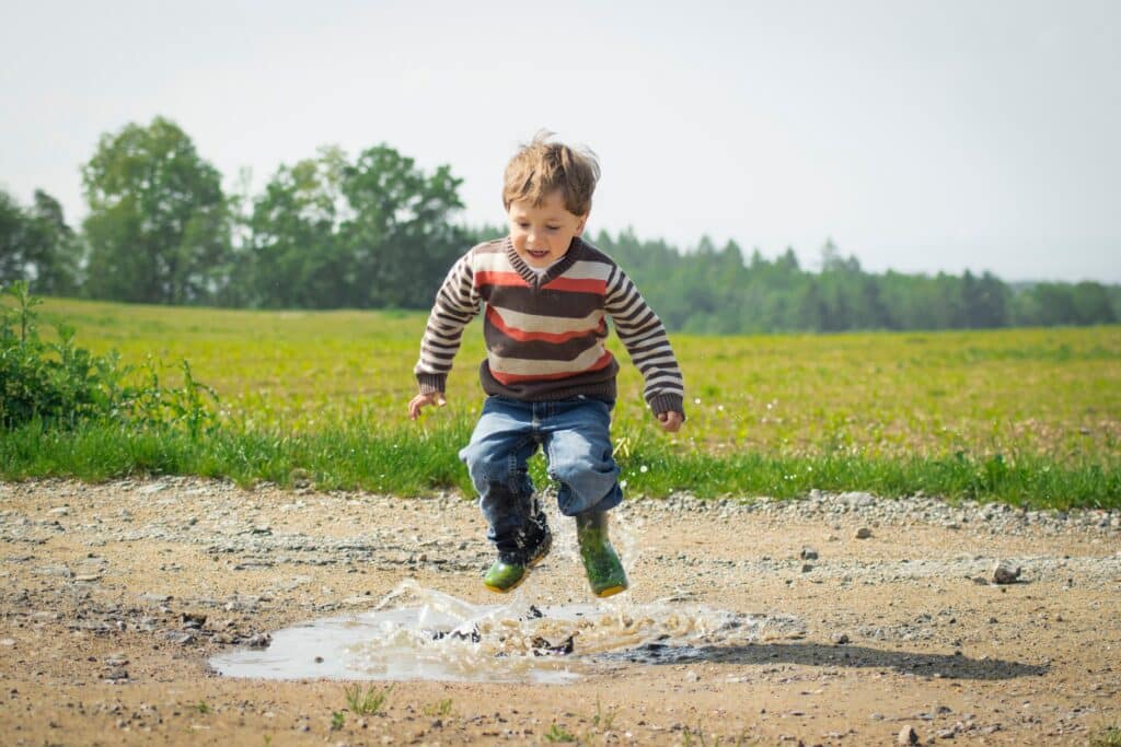 Little boy jumping in a puddle