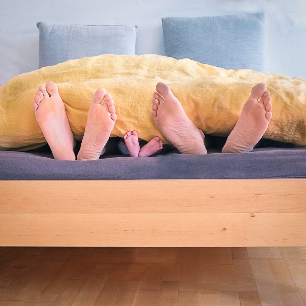 Adult and children feet poking out of the bottom of a bed