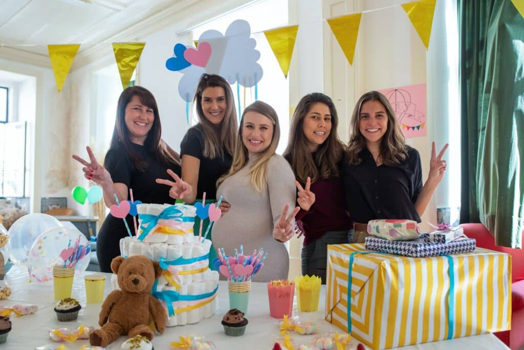 Women pose at a baby shower with a diaper cake