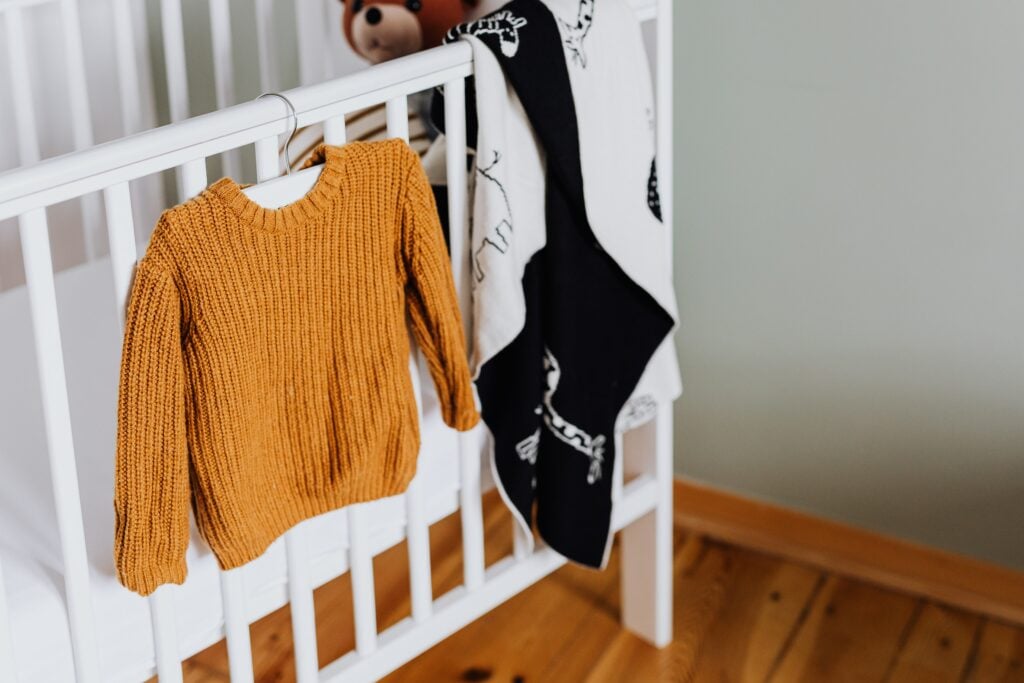 Baby crib with blanket and clothes hanging on it