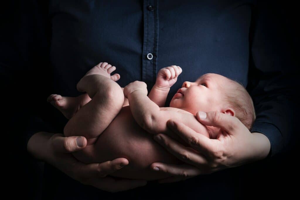 Tiny newborn being held by father