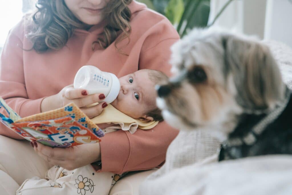 Mom feeding baby with bottle next to dog