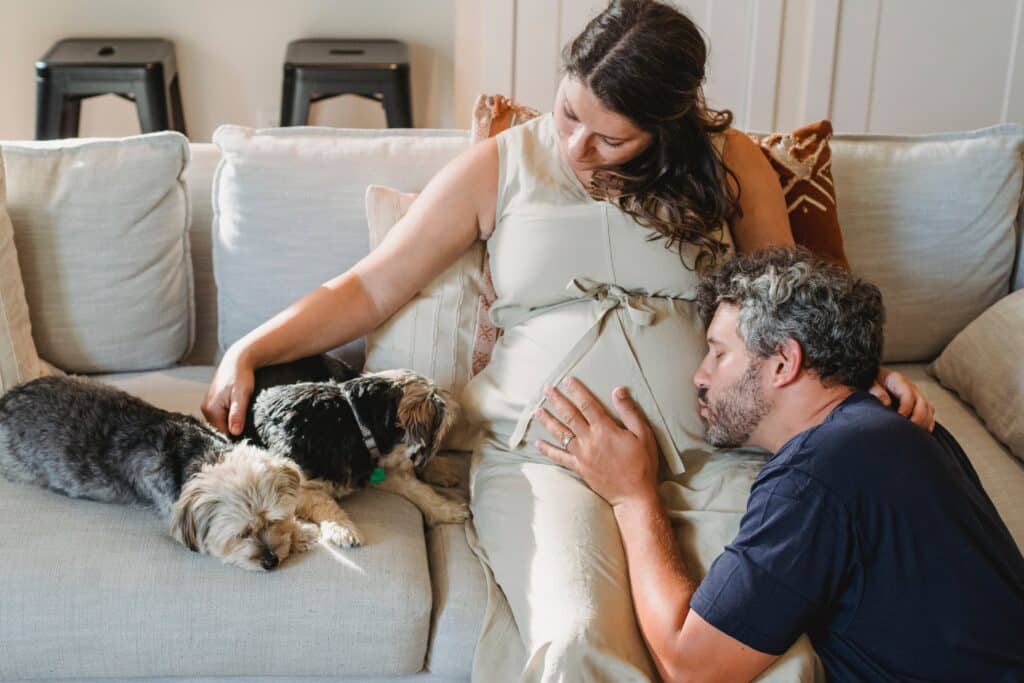 Pregnant woman and husband on couch with dog