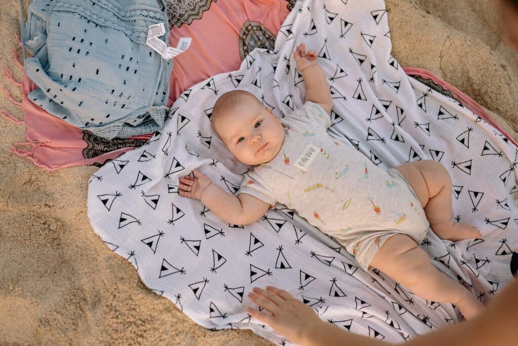 Infant laying on a blanket in the sand