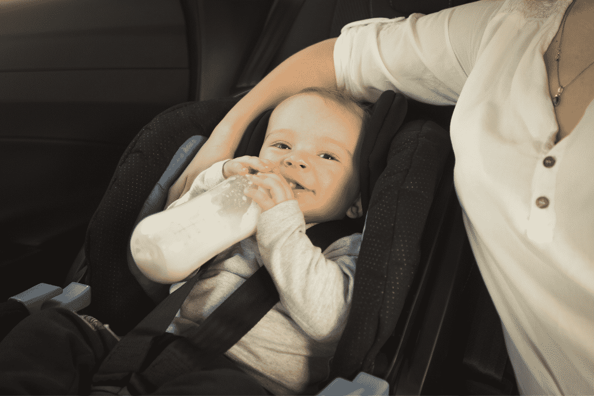 Baby drinking out of a bottle in a car seat