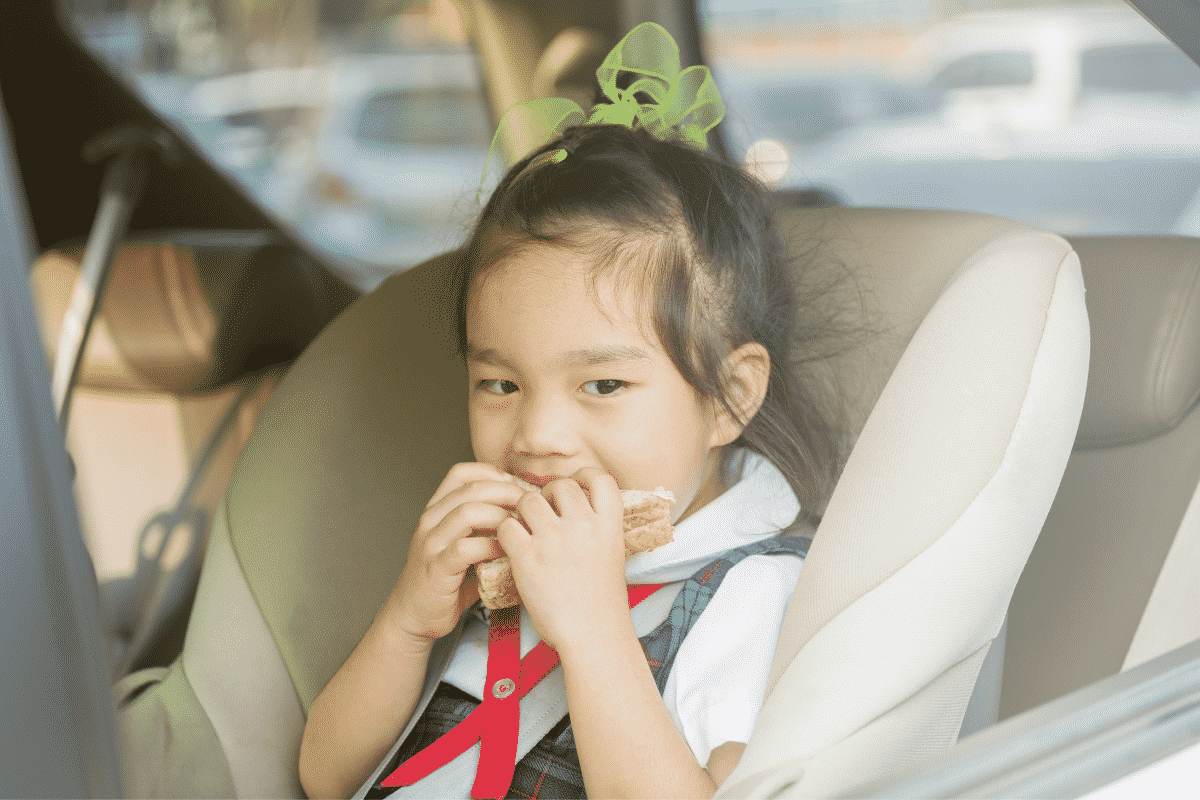 Child eating a snack in their car seat