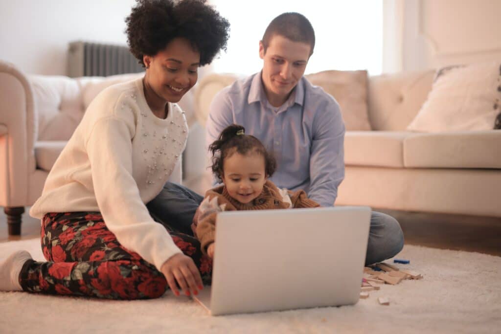 Parents sitting with toddler in front of laptop