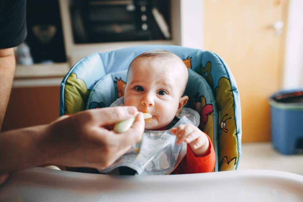 Baby eating in highchair with bib on
