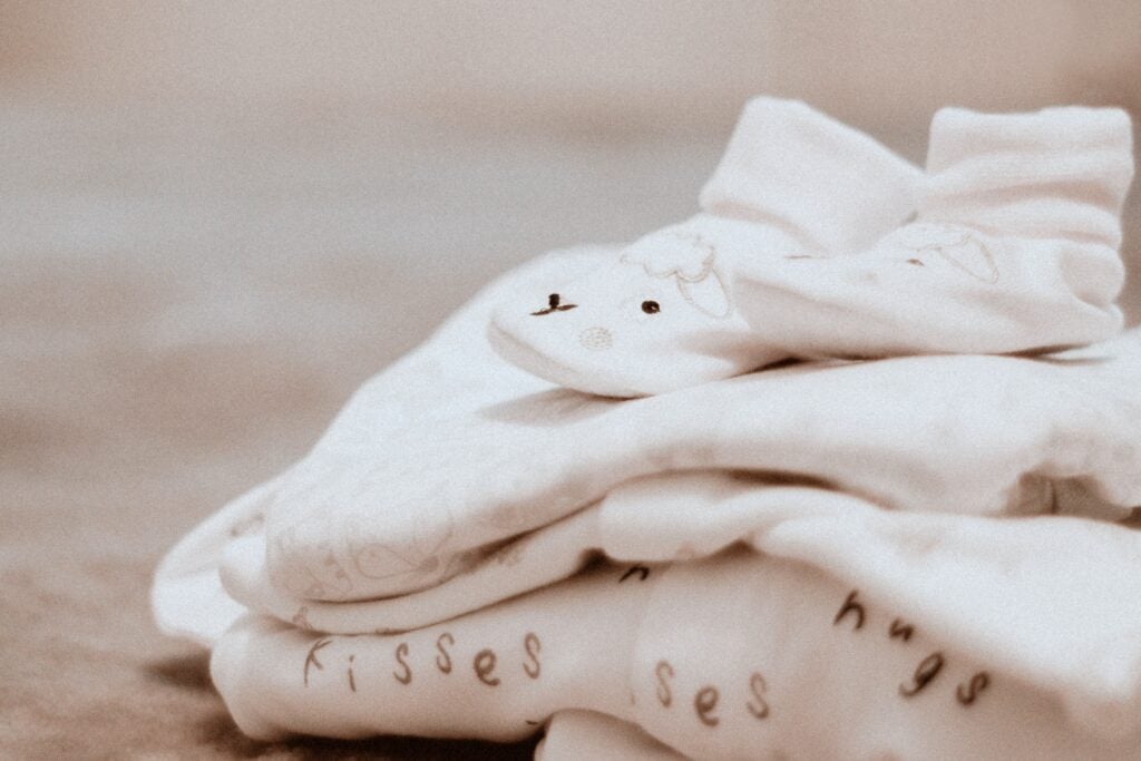 Folded baby clothes on top of bed