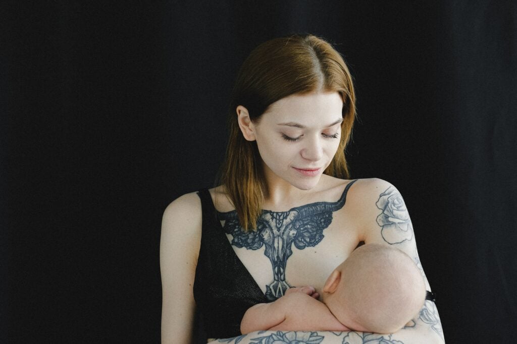 Woman with tattoos breastfeeding her baby