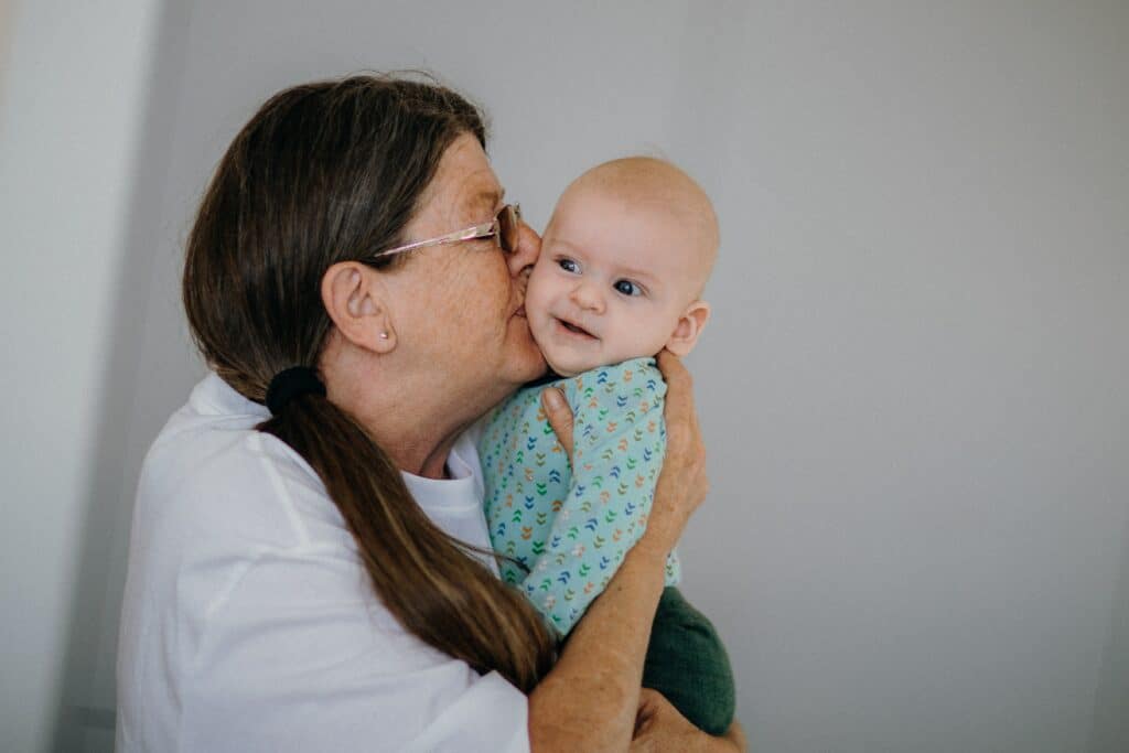 Grandmother holding and kissing infant grandchild