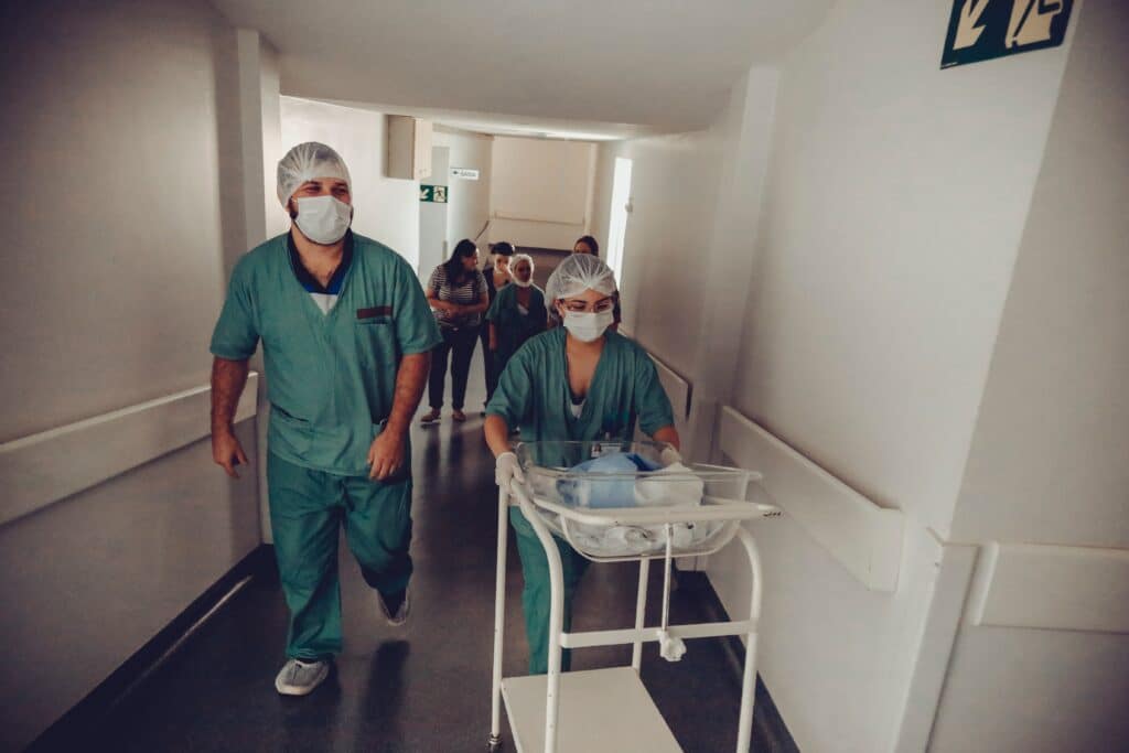 Small baby being pushed through hospital by medical staff