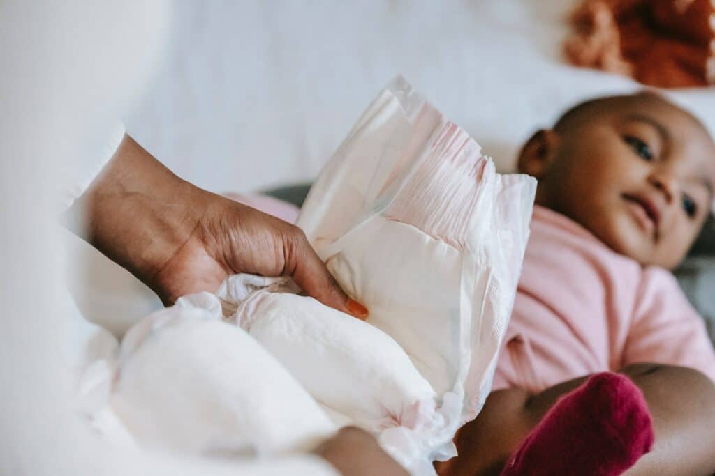 Parent changing baby's diaper on bed