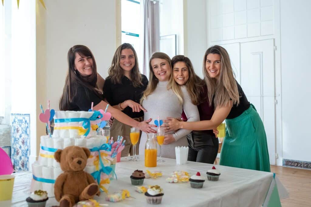 A group of women pose in front of a table with a diaper cake and stuffed bear