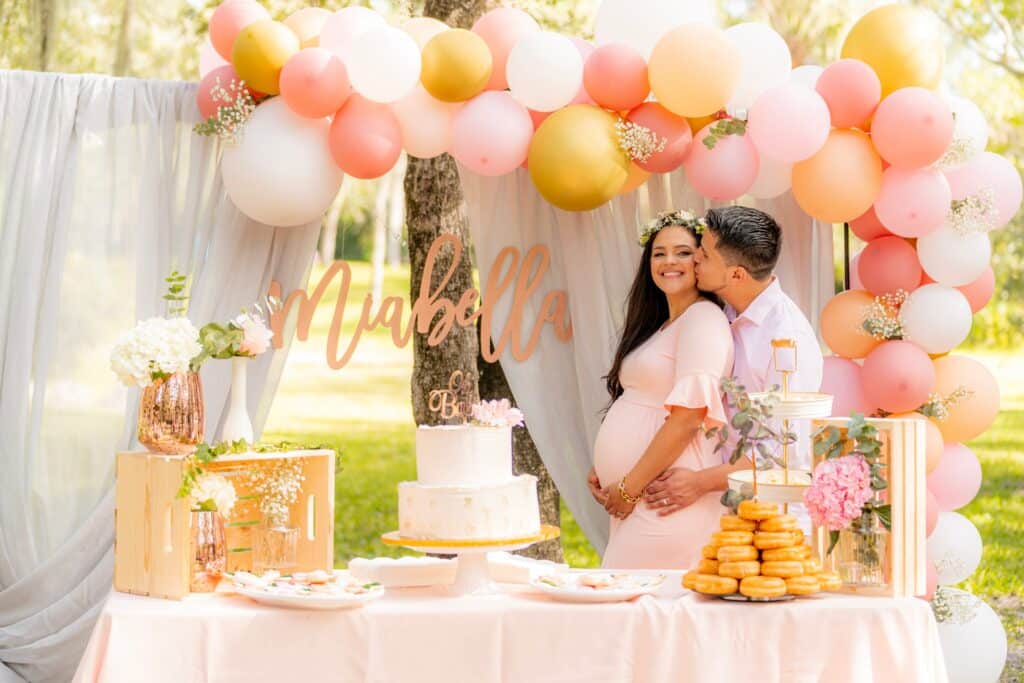 Soon-to-be parents pose in front of a backdrop at a baby shower
