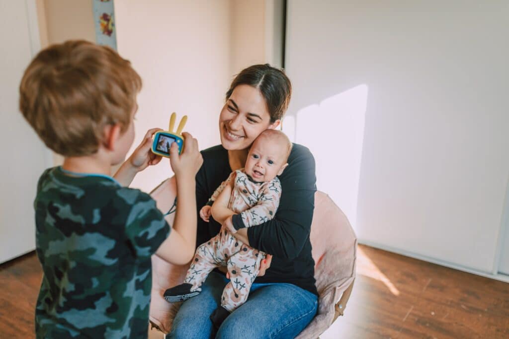 Child taking picture of mom and new baby