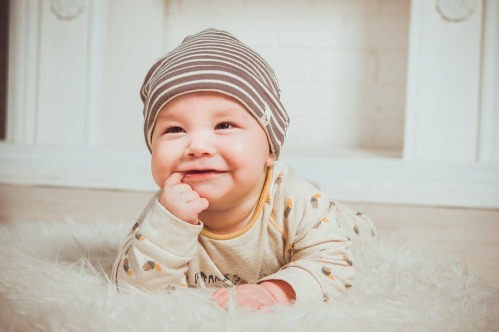 Baby smiling with finger in his mouth