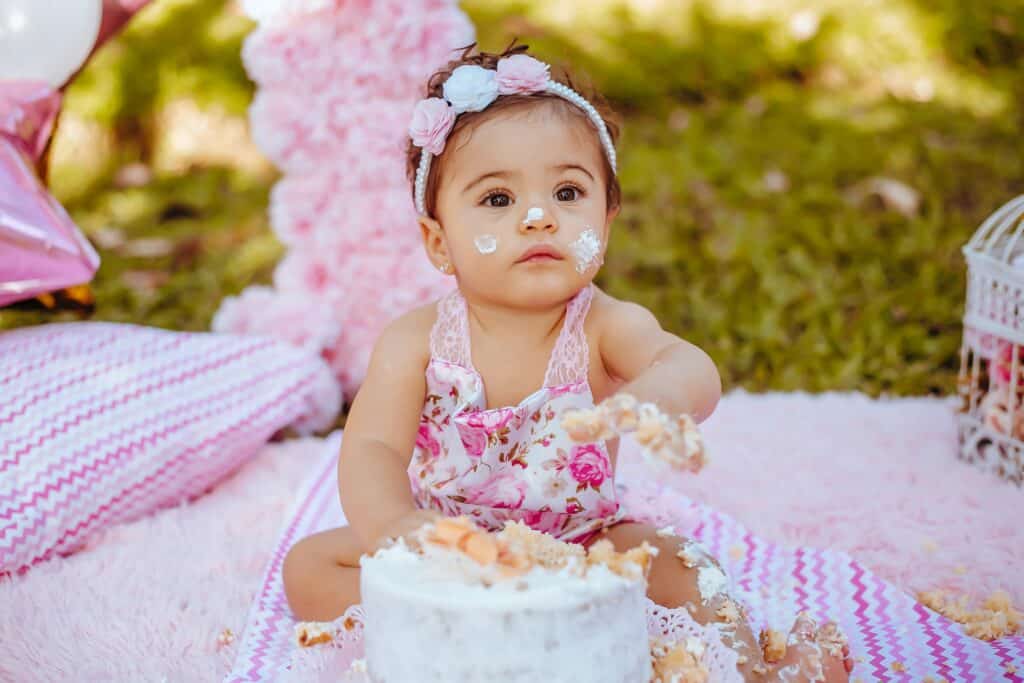 Baby girl eating birthday cake with earrings