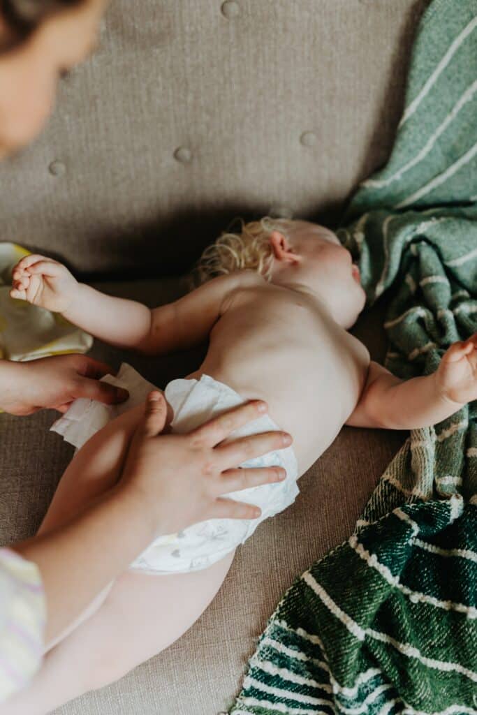 Person changing a squirmy toddler's diaper