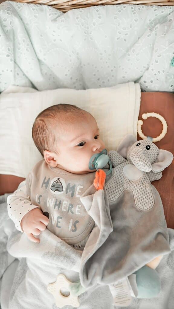 Newborn baby with pacifier attached to a toy