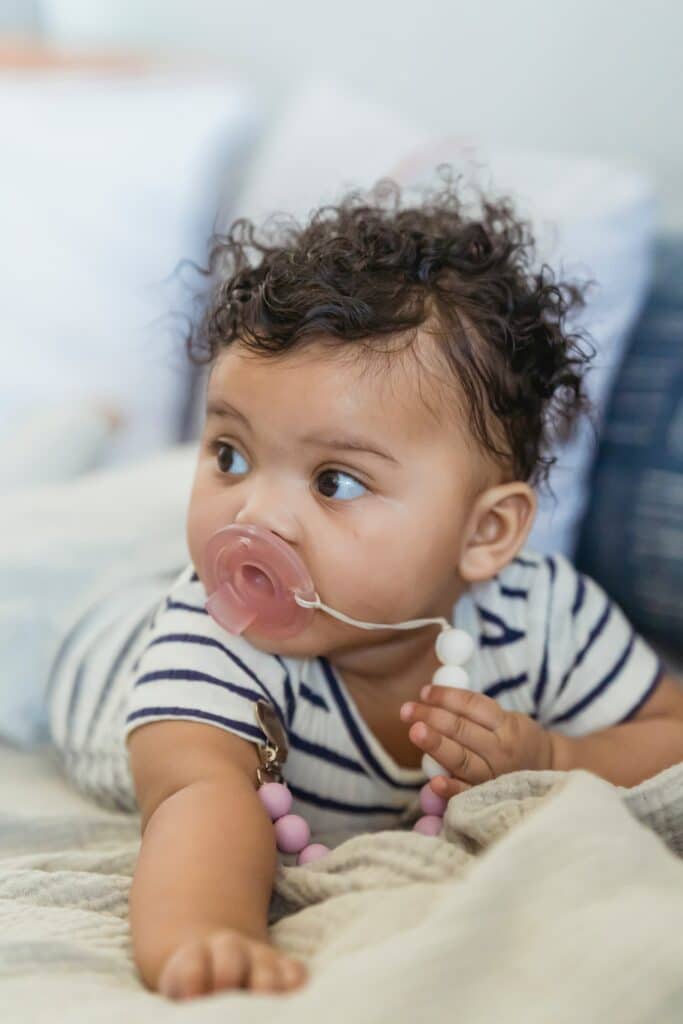 Infant during tummy time with a pacifier and pacifier leash