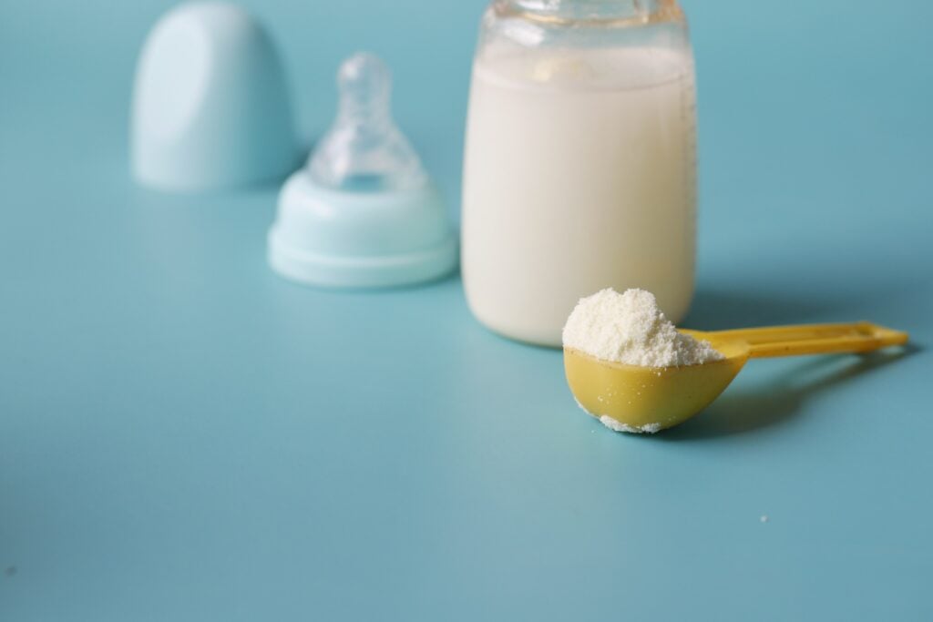 Baby formula powder in a scoop with a bottle