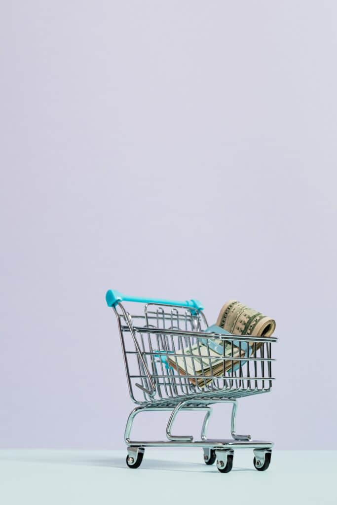 A shopping cart with a wad of cash in it