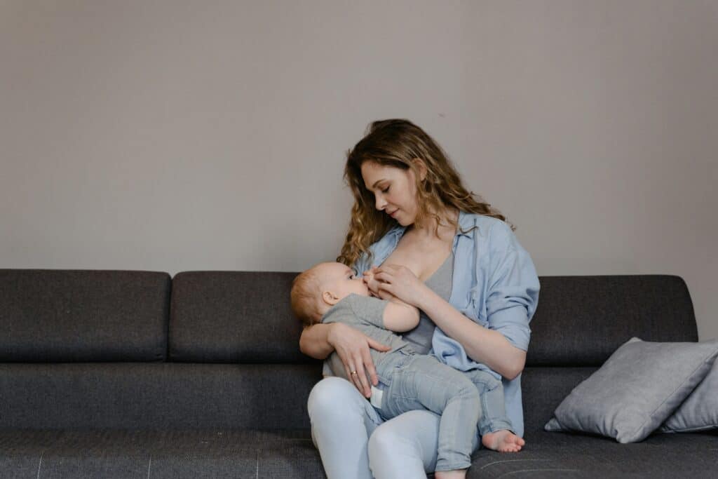 Woman breastfeeding her baby while sitting on a couch