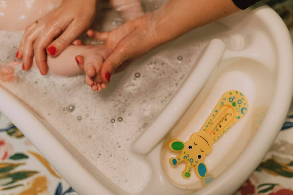 Baby being washed in a baby tub with a thermometer
