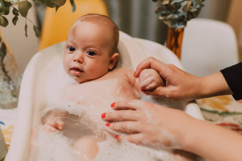 Infant taking a bath in a baby tub