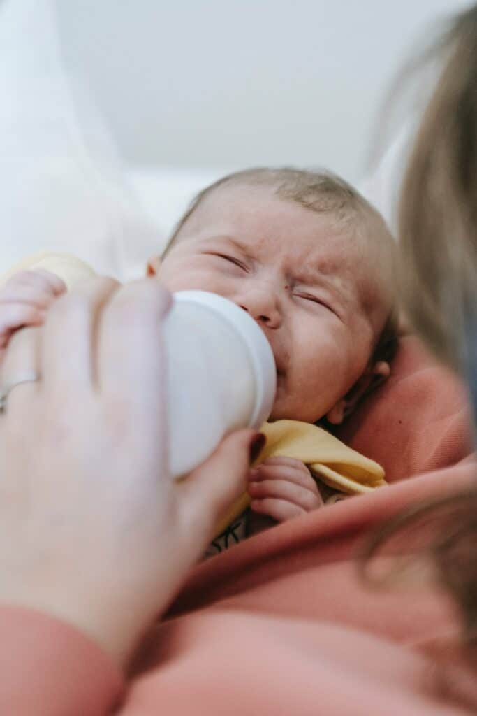 Newborn baby being bottle fed by her mother