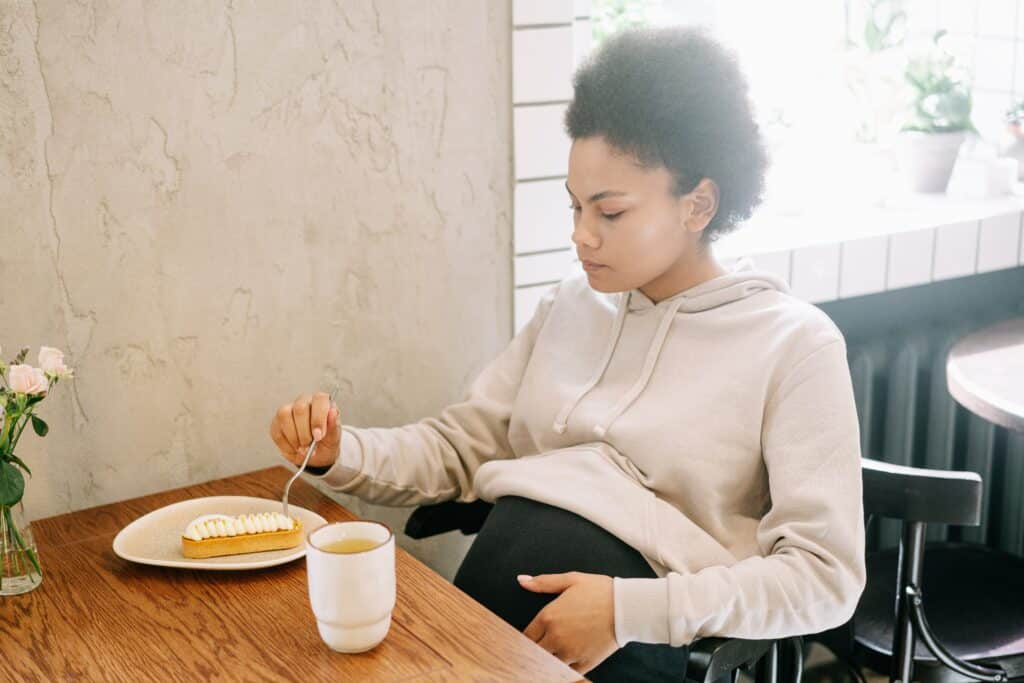 Pregnant woman eating a slice of pie at a table