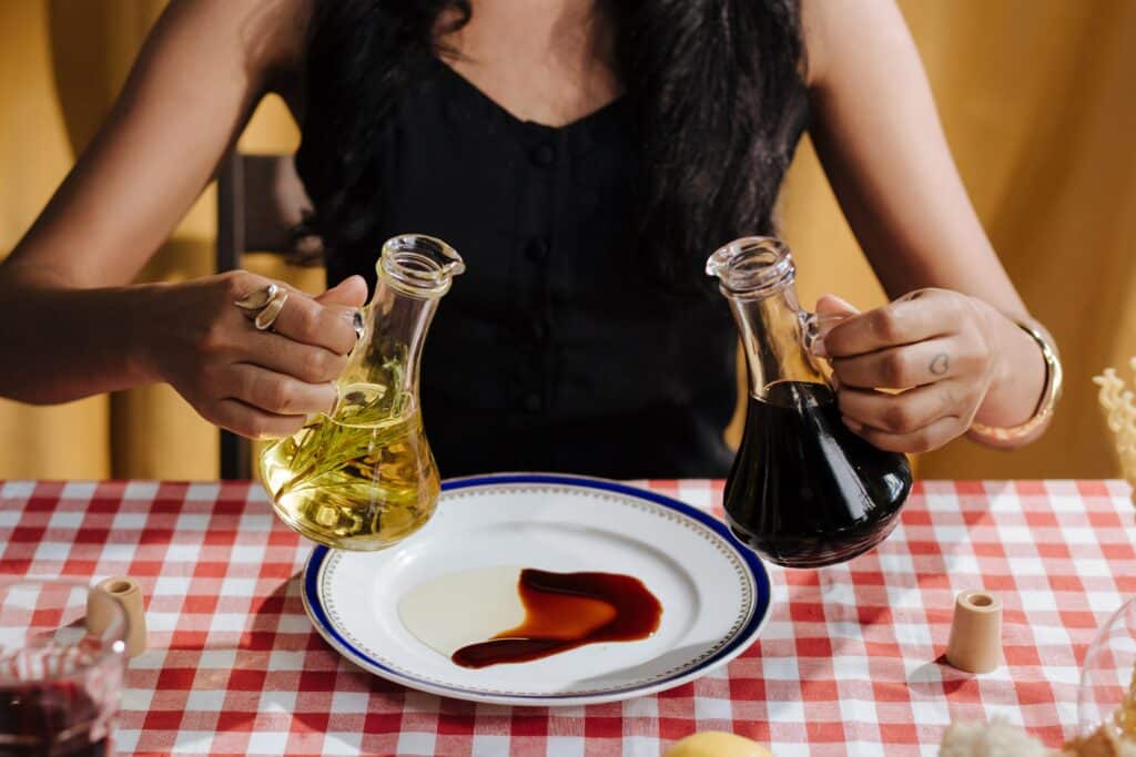 Woman pouring olive oil and vinegar on plate