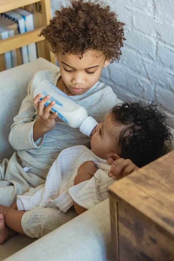 Sibling feeding a baby with a 8-ounce bottle