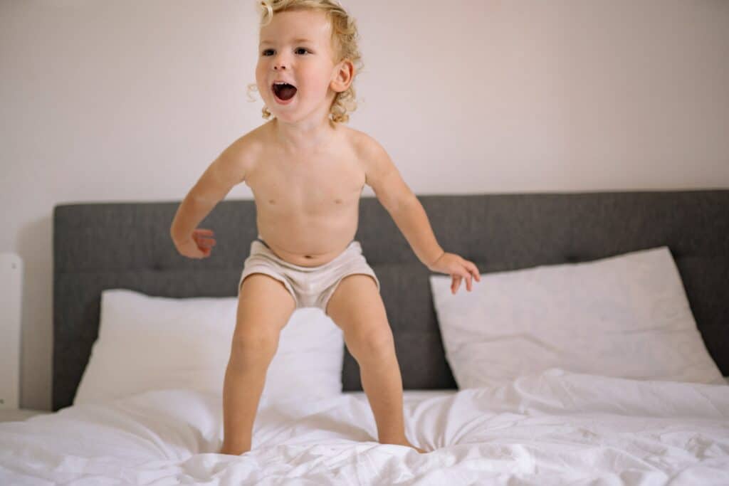 Toddler jumping on the bed in training pants