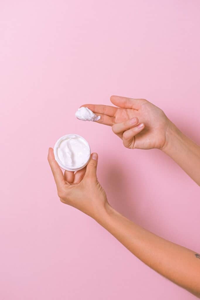 Woman holding a small tub of lotion