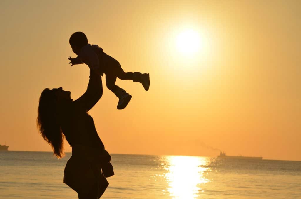 silhouette of mother carrying her baby at beach